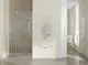 Weißer Kermi-Heizkörper mit Längsrippen, links montiert, an einer hellen Wand im Badezimmer. Dusche im Hintergrund, moderne Einrichtung.